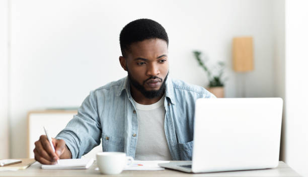 arbeitsloser mann mit laptop auf der suche nach freien stellen online im internet - arbeitssuche stock-fotos und bilder