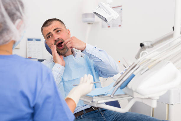 Unhappy american man in medical chair complains of toothache stock photo