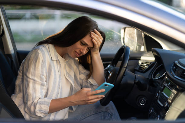 Unhappy girl cry reading sms message in smartphone driving car. Upset female break up with boyfriend stock photo
