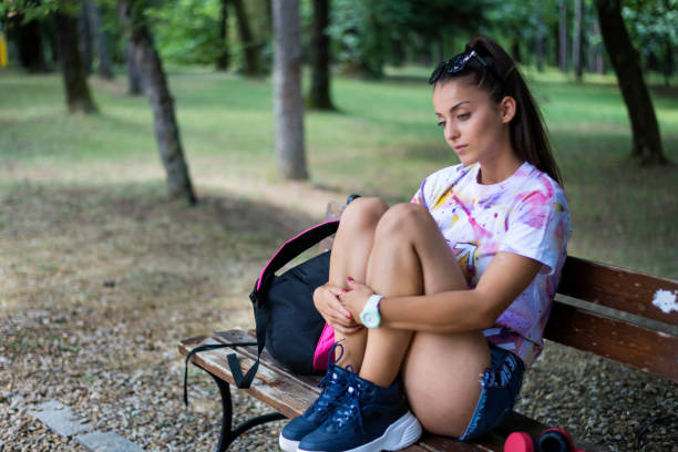 Unhappy girl sitting at bench stock photo