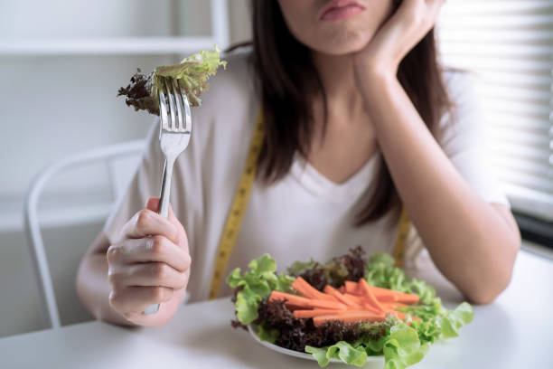 Unhappy women is on dieting time, girl do not want to eat vegetables. stock photo