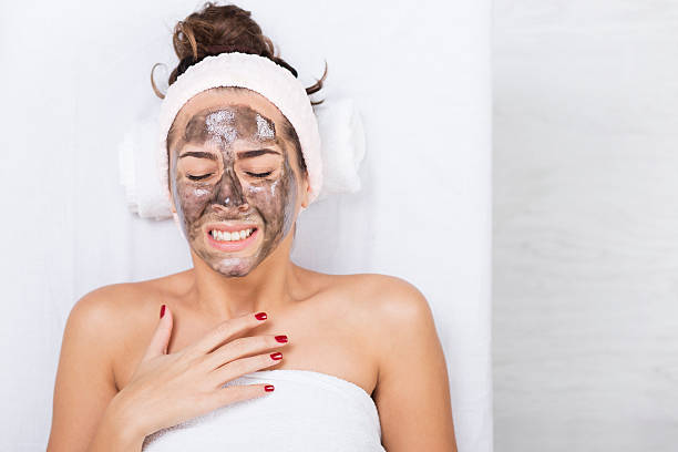 Unhappy young woman in a spa with black facial mask stock photo