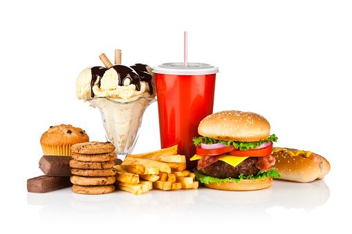 Group of unhealthy food isolated on white background. The composition includes, candy bar, muffin, cookies, ice cream, french fries, a glass of soda, hamburger and a hot dog. This is an unhealthy food rich in carbohydrates, sugar and calories.  DSRL studio photo taken with Canon EOS 5D Mk II and Canon EF 70-200mm f/2.8L IS II USM Telephoto Zoom Lens