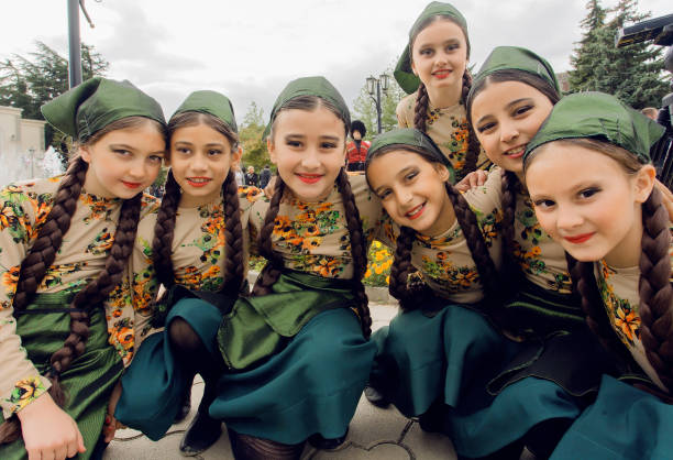 Unidentified girls in traditional Georgian costumes posing in crowd of the party stock photo