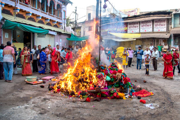 unidentified people celebrating Holika Dahan by worshiping of wood logs or coconut. also known as the festival of colors Holi or the festival of sharing stock photo