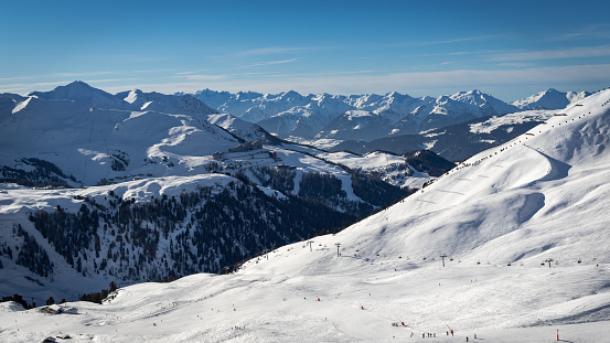 Unidentified people skiing on ski slopes in the winter ski resort La Plagne in French Alps. Plagne Aime 2000 in background.