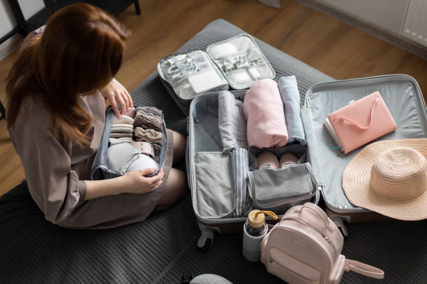 Unidentified woman puts lingerie in trip storage container use konmari method packing suitcase stock photo
