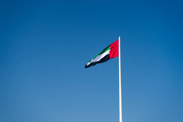 A United Arab Emirates flag A United Arab Emirates flag flying against clean and tranquil sky. UAE celebrates it's national day on 2nd December every year. united arab emirates flag stock pictures, royalty-free photos & images