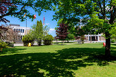 Saint John, New Brunswick, Canada - June 23, 2019: Trees and the shady lawn at the University of New Brunswick (UNB), Saint John campus. The Campus buildings in the background are partially obscured by trees. Chares and benches are present for people to rest on. UNB was founded by Loyalist settlers in 1785, the Saint John campus pictured was founded in 1964. The Saint John campus has expanded significantly in recent years.
