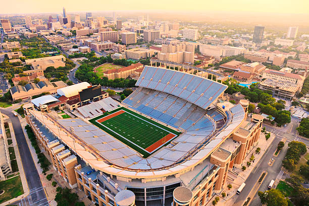 University of Texas Football Stadium - Aerial View Aerial view from a helicopter of UT Football Stadium at sunset, with Austin skyline and University of Texas campus in background. All signs and logos removed - suitable for commercial use. universities in texas stock pictures, royalty-free photos & images