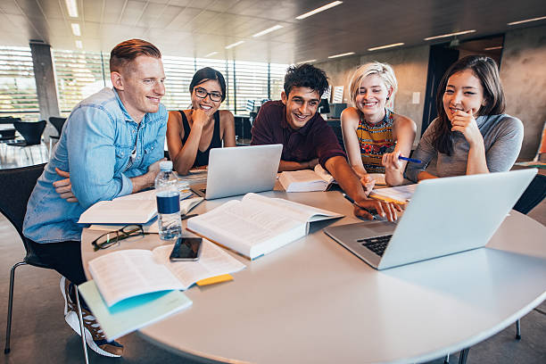 University students in cooperation with their assignment Multiethnic group of young people studying together at a table looking at laptop. Young students in cooperation with their school assignment. jacob ammentorp lund stock pictures, royalty-free photos & images