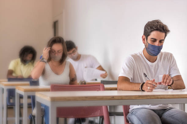University students in mask doing pre-vestibular test for ENEM stock photo
