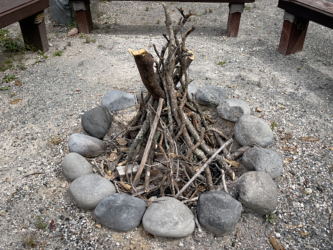 A teepee-style campfire surrounded by bench seats