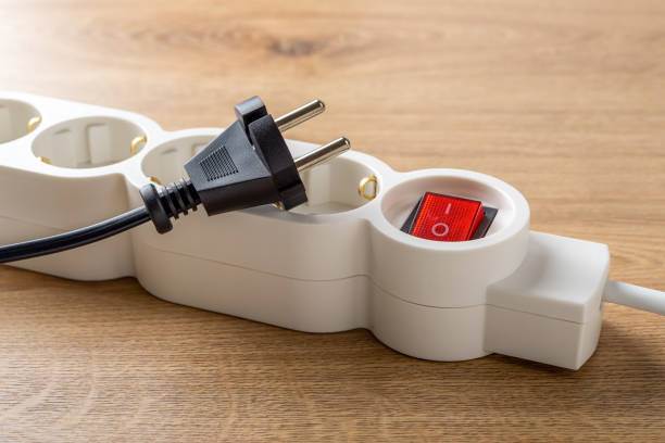 Unplugged electric appliance plug over switched off white power strip on the floor. Power crisis. Increasing the energy costs, heating costs, save electricity concepts. Power outage. stock photo
