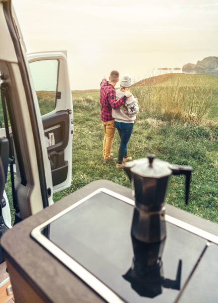 Unrecognizable couple traveling in camper van looking coastline landscape stock photo