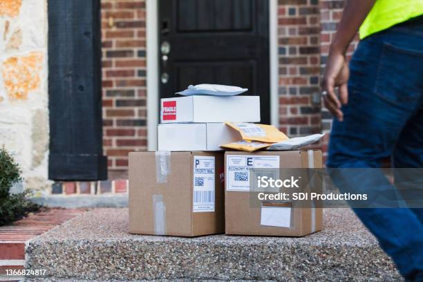 Unrecognizable delivery man approaches stack of mail for pick-up