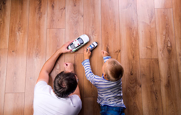 Unrecognizable father with his son playing with cars Unrecognizable father with his son playing with cars. Studio shot on wooden background. human limb stock pictures, royalty-free photos & images
