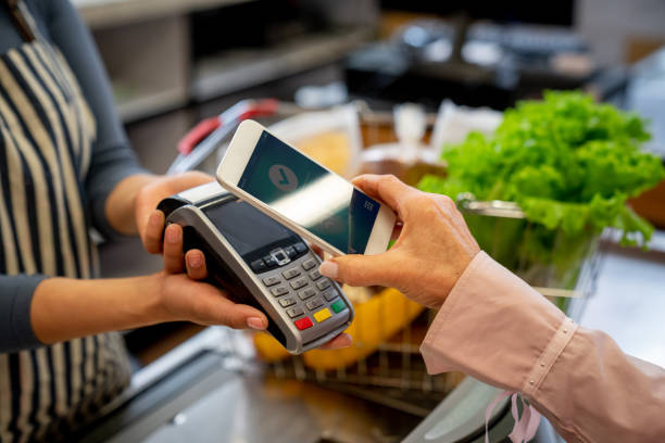 인식할 수 없는 여성 고객 스마트폰으로 식료품에 대 한 지불 - 지불 뉴스 사진 이미지