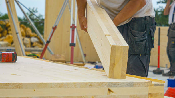 CLOSE UP: Unrecognizable male builder picks up a CLT beam from a workbench. stock photo