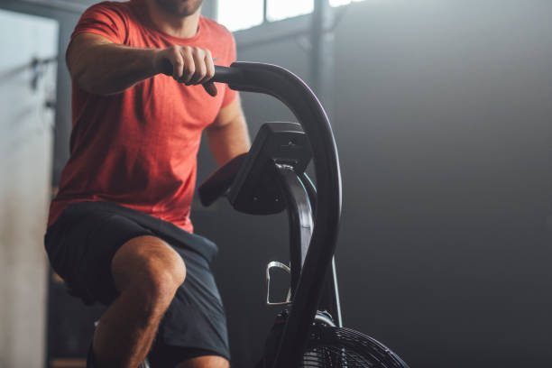 Unrecognizable  Man Doing Exercise on a Gym Stationary Bike, gym Concept Endurance trainings: anonymous fit man working out on an exercise bicycle. exercise machine stock pictures, royalty-free photos & images