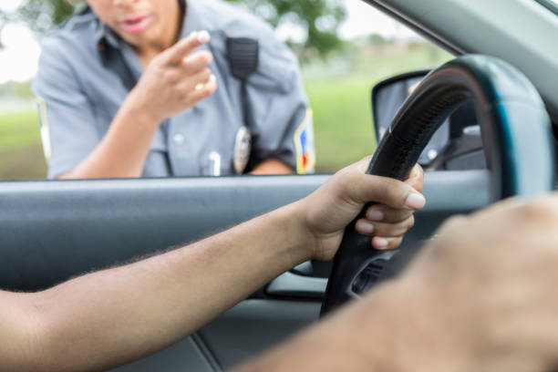 Unrecognizable man is pulled over for speeding Unrecognizable female police officer talks with man she pulled over for speeding. She is pointing while talking to the man. rule breaker stock pictures, royalty-free photos & images