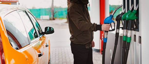 Unrecognizable man refueling car from gas station filling benzine gasoline fuel in car at gas station. Petrol high prices concept stock photo
