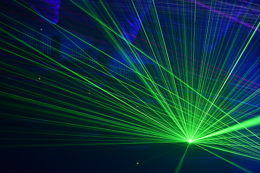 Unrecognizable people watching a beautiful laser show with multicolored lights