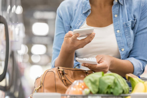 unrecognizable supermarket customer uses smart phone and paper list - change habits imagens e fotografias de stock