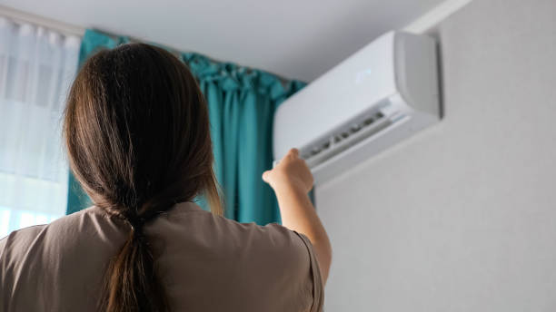 Unrecognizable woman turns on the air conditioner, back view stock photo