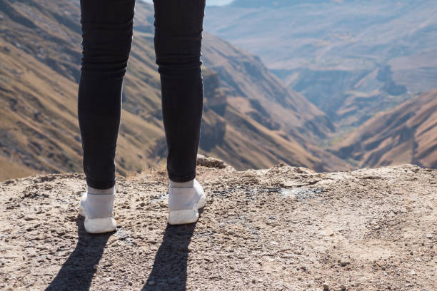 Unrecognizable young woman stands on the edge of the cliff stock photo