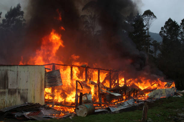 flames and smoke rise from a burning building on a farm near...