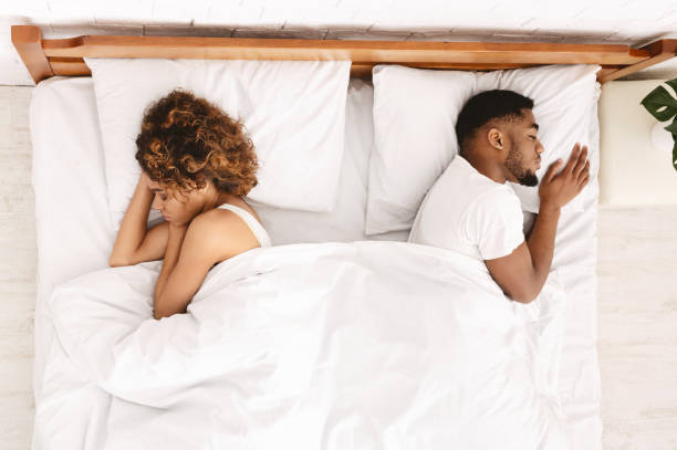 Upset couple sleeping separately on their bed Relationship problem. Upset african-american couple sleeping separately on their bed, top view, free space couple divorce photos stock pictures, royalty-free photos & images