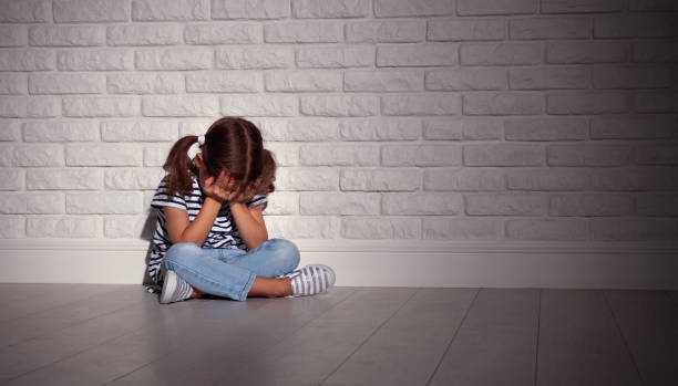 upset sad sad child girl in stress cries at an empty dark wall  violence of children stock pictures, royalty-free photos & images