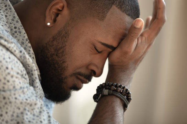 Upset stressed young african american man coping with strong headache Upset stressed young african american man coping with strong headache concept, upset exhausted black guy feeling frustrated depressed tired touching forehead suffer from migraine, close up side view grief stock pictures, royalty-free photos & images