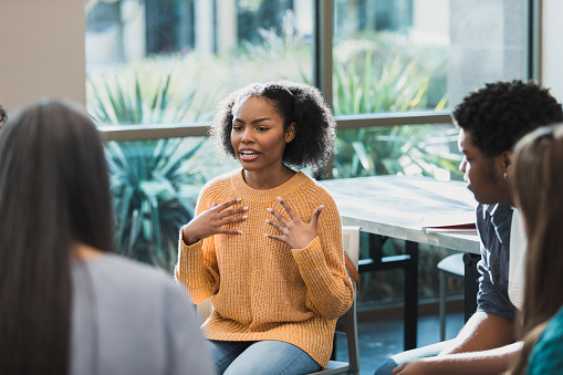 During a group therapy session for teenagers, a teenage girl discusses her emotions.