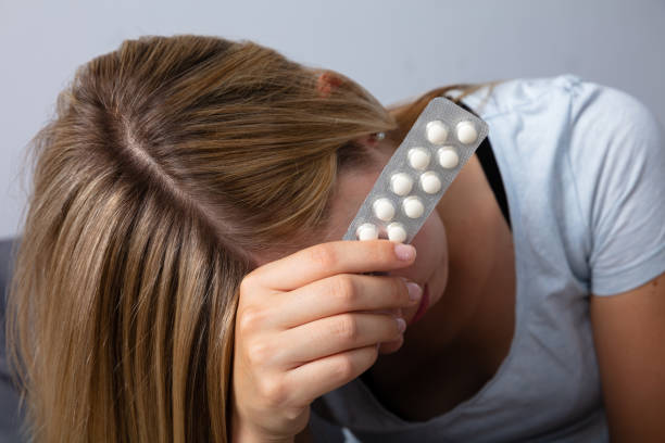 Upset Woman Holding Medicine Close-up Of A Young Upset Woman Holding Medicine abortion pill stock pictures, royalty-free photos & images