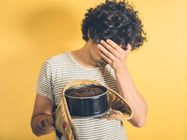 Upset young man with burnt cake stock photo