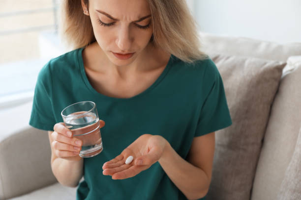 Upset young woman with abortion pill and glass of water at home, closeup Upset young woman with abortion pill and glass of water at home, closeup abortion pill stock pictures, royalty-free photos & images
