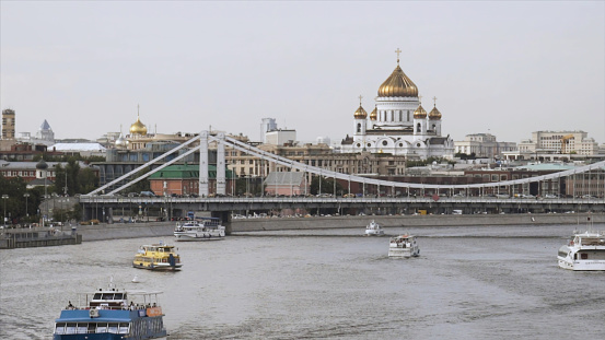 Urban landscape with bridge over river on background of Church. Action. Beautiful panorama of city with bridge over river and ships on background of moving city and Church.