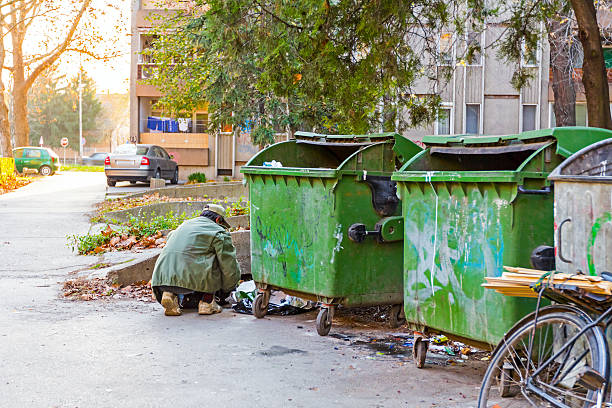 Urban Poverty Homeless man with his bike investigates garbage. scavenging stock pictures, royalty-free photos & images