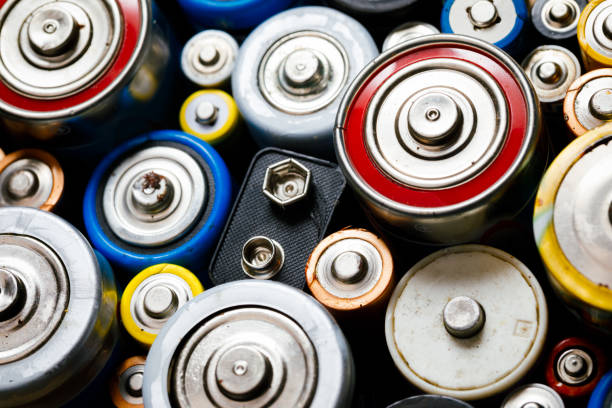 Used Alkaline batteries toxic waste recycling and ecology issues concept background Dumped used Alkaline batteries of various types (C AA AAA D 9V) ready for recycling - toxic waste and environmental issues concept battery stock pictures, royalty-free photos & images