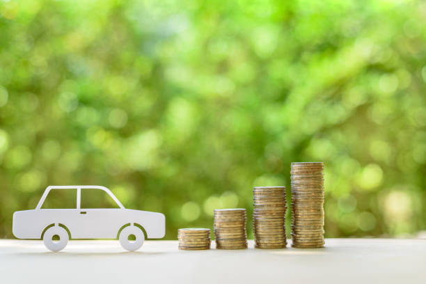 Used and second hand vehicle / car or auto loan, financial concept : Sedan car and rows of coins on a table, depicts money loan or borrowing fund to buy a new or old car for personal or individual use stock photo