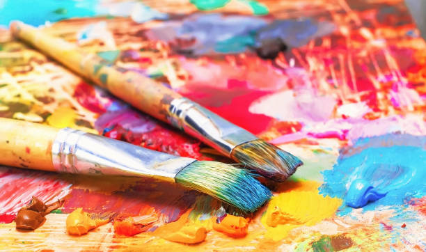 Used brushes on an artist's palette of colorful oil paint for drawing stock photo