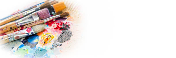 Used paintbrushes on a colorful painter palette. Paint concept panoramic background stock photo