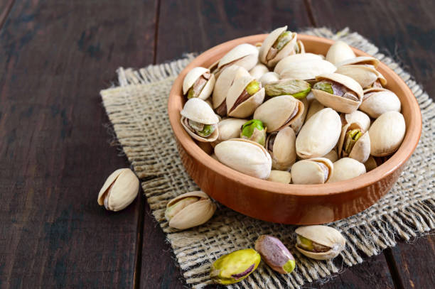 Useful nuts - pistachios in a ceramic bowl on a dark wooden background. Useful nuts - pistachios in a ceramic bowl on a dark wooden background. pistachio stock pictures, royalty-free photos & images
