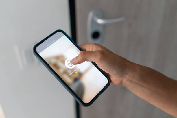 Using a smartphone to lock the door of a house - smart home technology stock photo