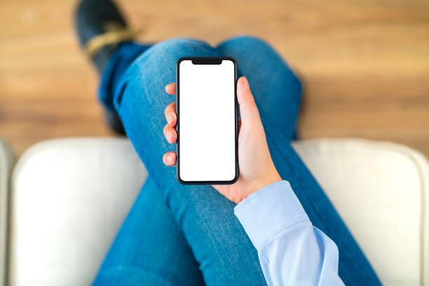Using blank screen smart phone Hand holding a blank white screen smart phone on a couch. blank screen stock pictures, royalty-free photos & images