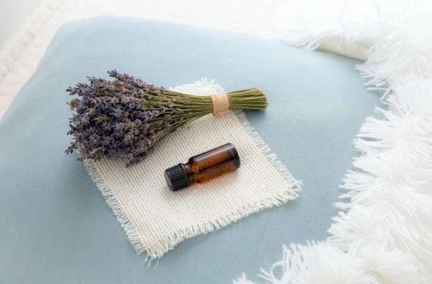 Using lavender flower essential oil for better good night sleep. Aromatherapy concept. Lavender oil and bouquet of dried lavender flowers on soft pillow in home bedroom. stock photo
