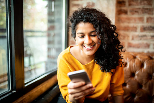 Using mobile phone. Young Indian woman using mobile phone at the bar online shopping photos stock pictures, royalty-free photos & images