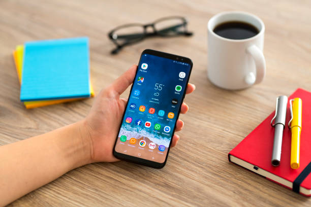 Using Samsung Galaxy smart phone İstanbul, Turkey - February 2, 2019: Hand holding a smart phone on a wooden desk. The smart phone is an Samsung Galaxy S9 plus. Samsung Galaxy is a touchscreen smart phone produced by Samsung Electronics. cyborg stock pictures, royalty-free photos & images